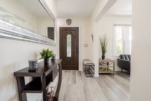 Ein modernes Wohnzimmer mit einem dunklen Holztisch, einem schwarzen Sofa und einer Topfpflanze.