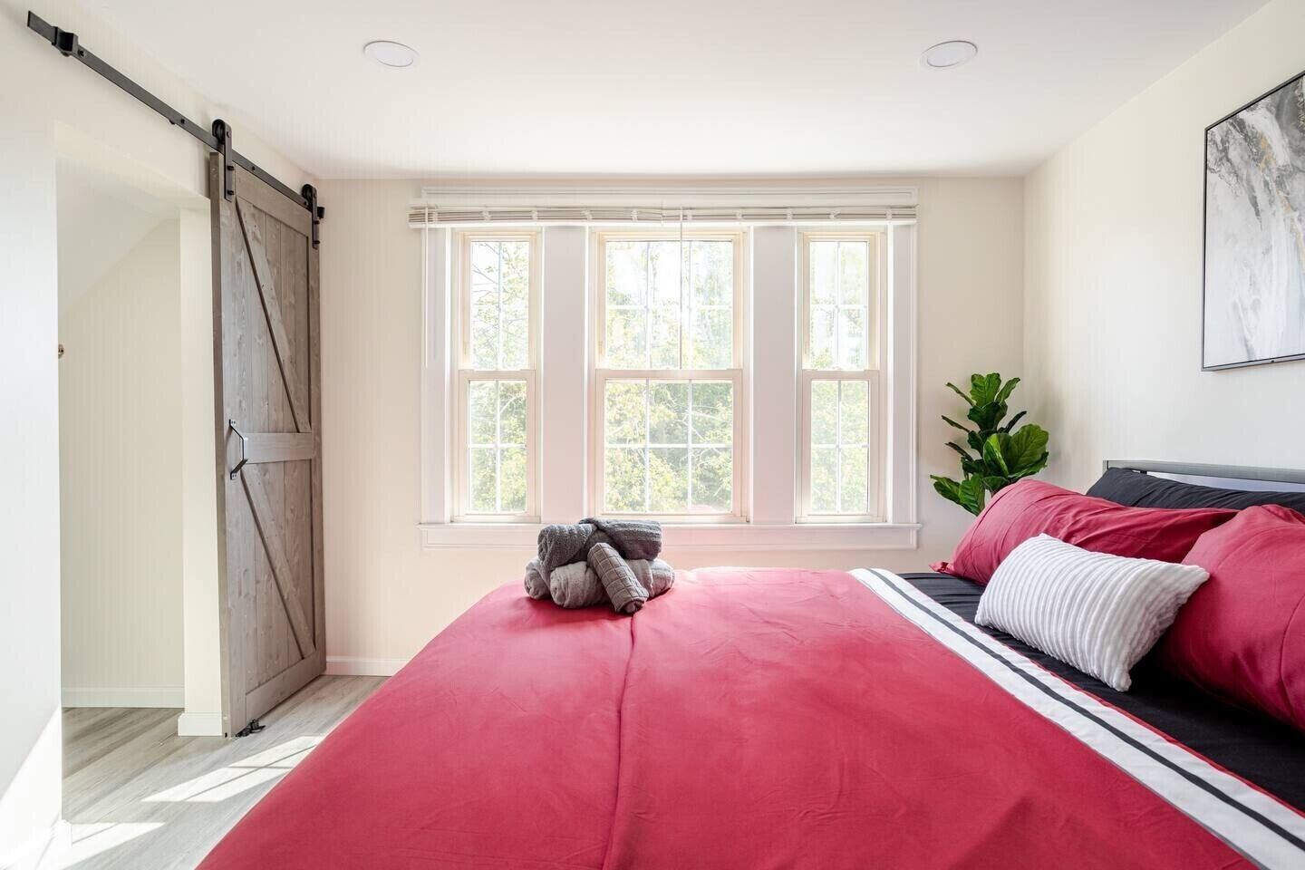Une chambre avec un grand lit, une porte coulissante et une fenêtre avec des stores.