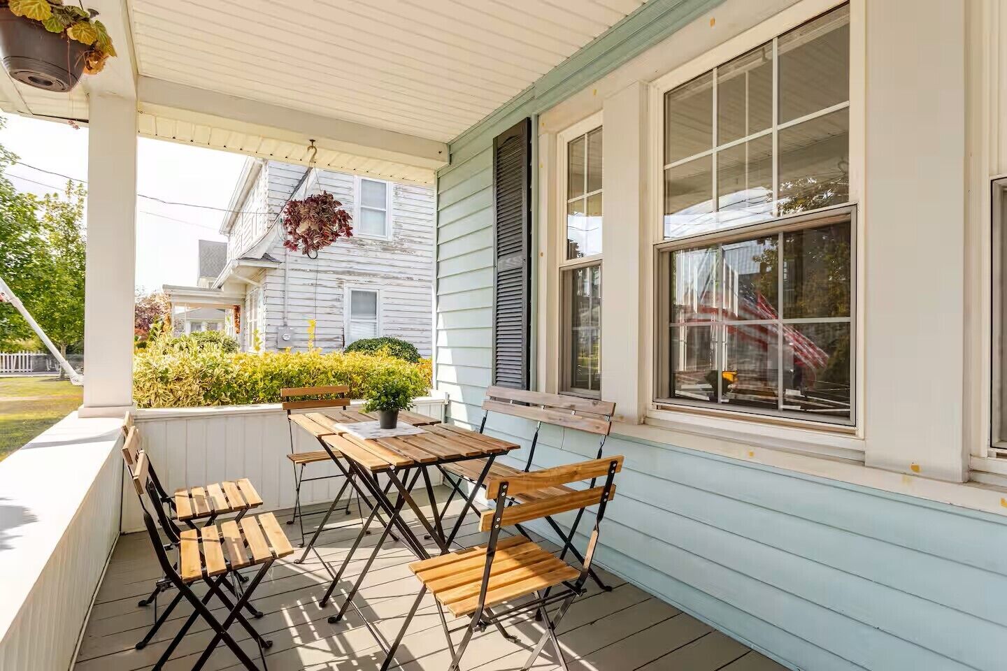 A covered porch with wooden furniture and a potted plant.