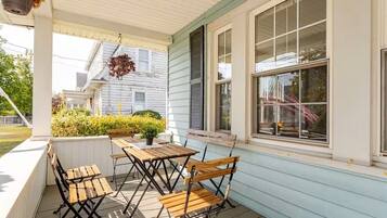 A covered porch with wooden furniture and a potted plant.