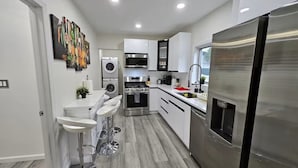 A modern kitchen with stainless steel appliances, white cabinetry, and a central island with bar stools.