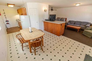 Een compacte leefruimte met een eethoek, kitchenette en zithoek.