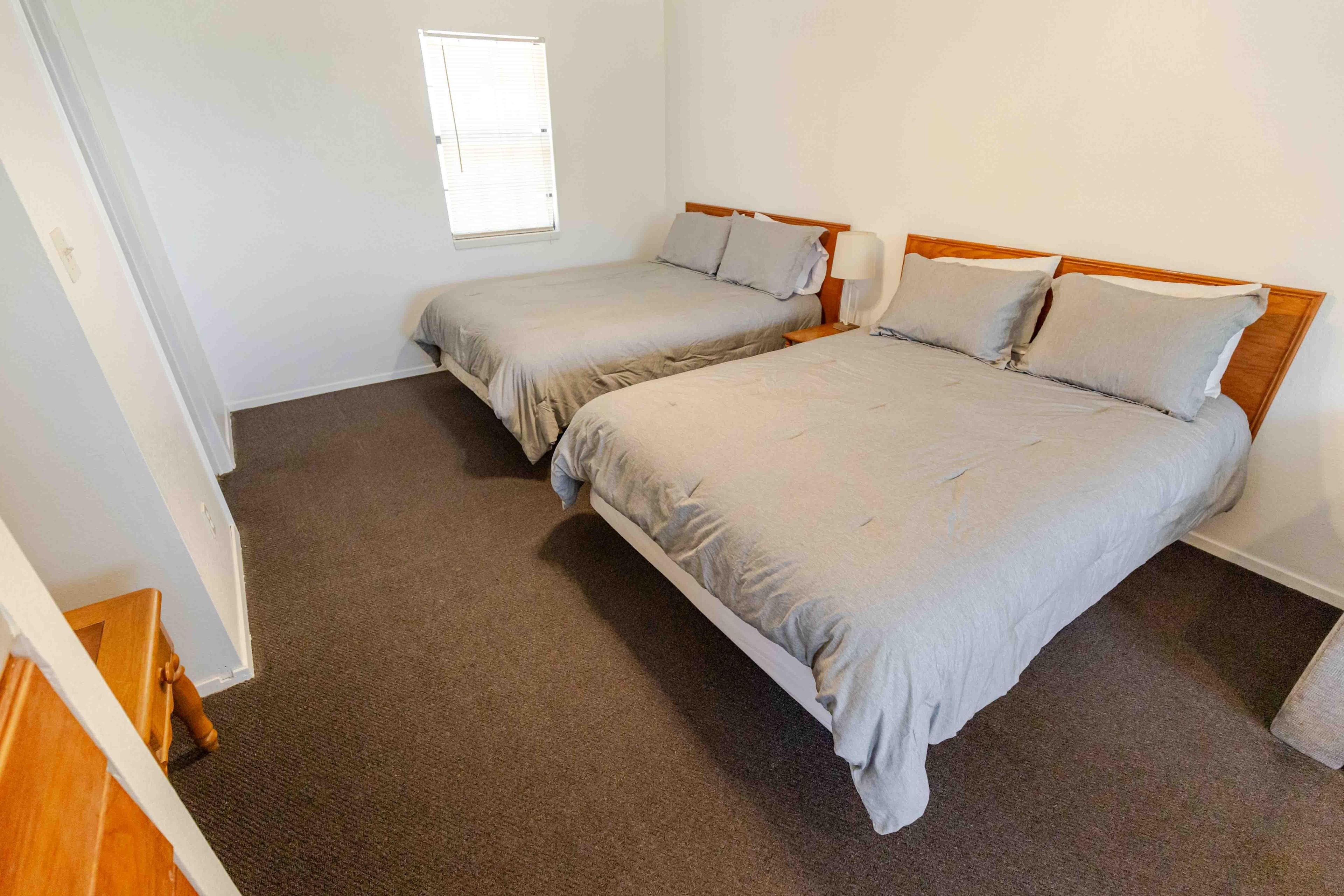Une chambre avec deux lits simples, une fenêtre et un sol recouvert de moquette.