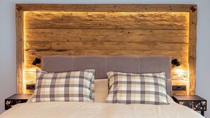 A bed with a wooden headboard, two bedside tables, and checkered pillows.