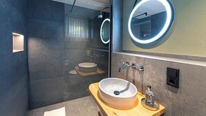A modern bathroom with a round mirror, a wooden vanity, and a built-in sink.
