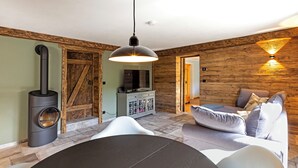 A modern living room with a stone fireplace, a dining table, and a sofa.
