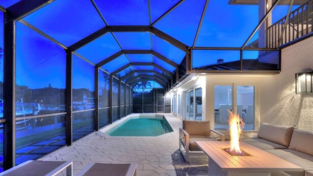 Zona de piscina exterior cubierta con una chimenea, asientos y vistas a la ciudad.