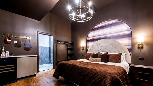 Un dormitorio moderno con una cama grande, un tocador con artículos de aseo, un vestidor amplio y un ventanal.