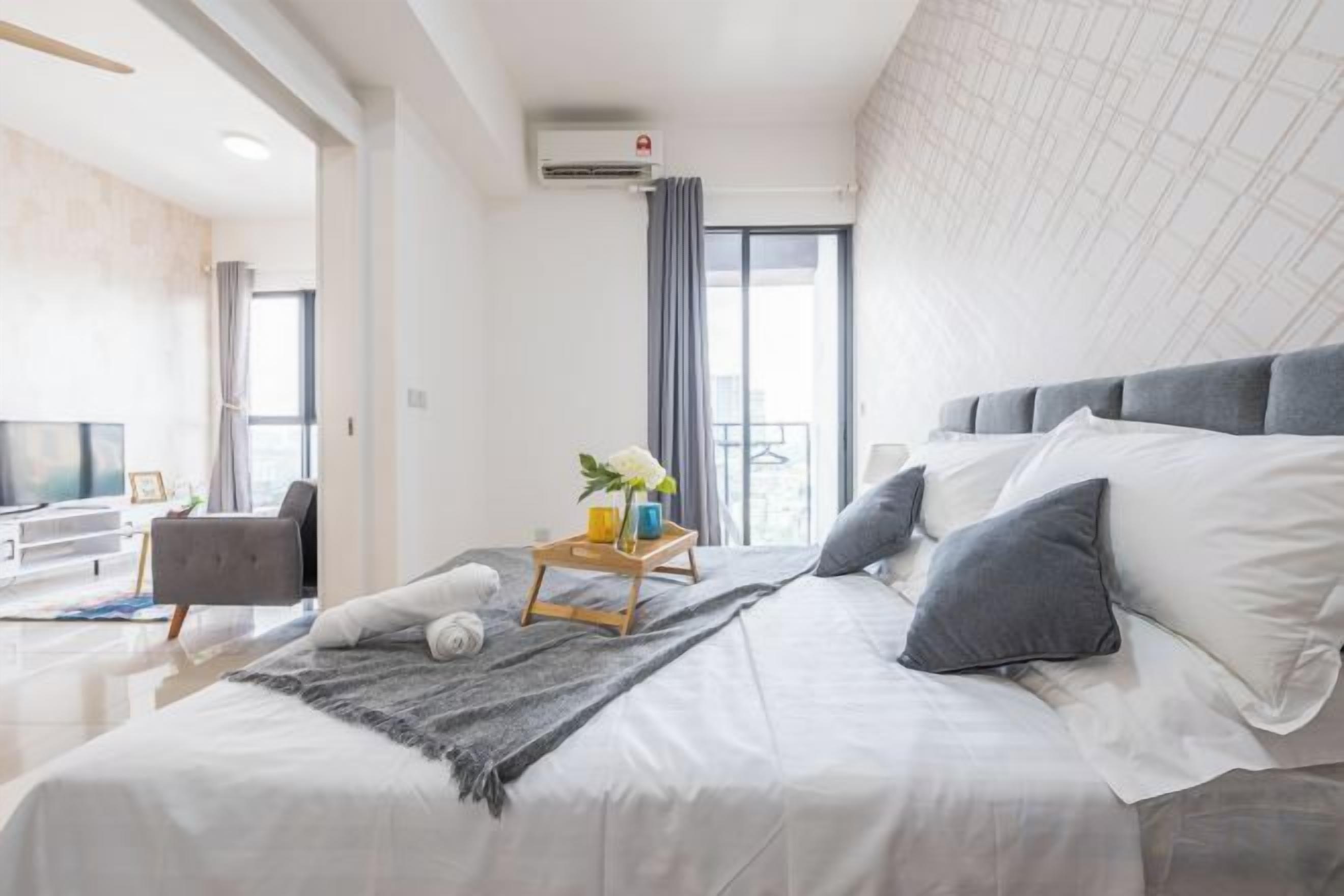 A modern bedroom with a large bed, a bedside table, a TV, and a balcony view.