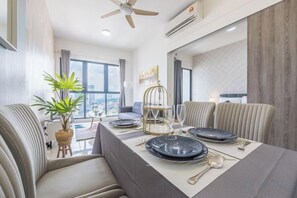 A dining area with a table set for four, a ceiling fan, and a large window with a city view. - Cozy Oasis near Ikea TRX Mall King Size Bed 100mb (Kuala Lumpur)