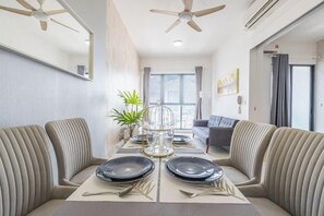 A dining area with a high ceiling fan, a dining table set for four, and a sofa in the background. - Cozy Oasis near Ikea TRX Mall King Size Bed 100mb (Kuala Lumpur)