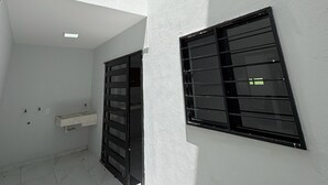 A modern building with a white exterior, a visible balcony, and a window with horizontal bars.