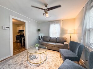 Una sala de estar con ventilador de techo, un sofá, una mesa de centro y una lámpara.