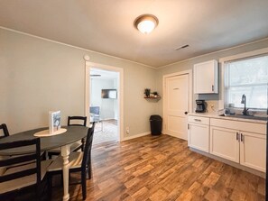 A compact kitchen with a dining area, a trash bin, and a laundry room.