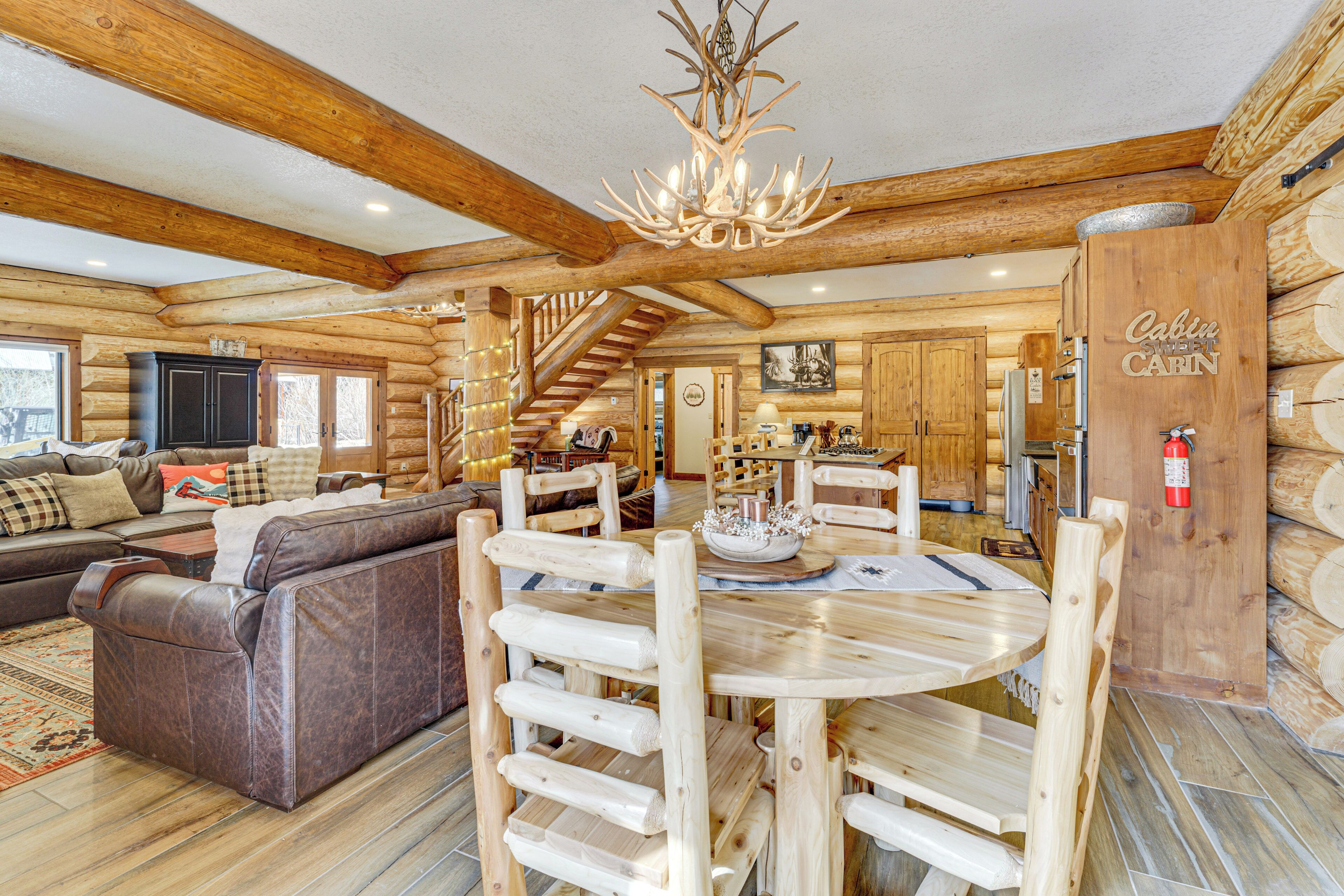 Ein Holzblockhaus-Interieur mit einem Holzessttisch, einer Couch und einer Treppe, die in die obere Etage führt.