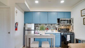 A kitchen with blue cabinets, a microwave, a stove, and a sink.