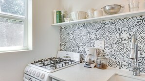 Een keuken met een gasfornuis, koffiezetapparaat en een spoelbak.