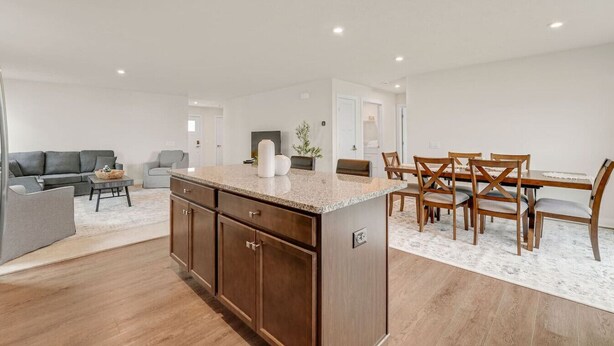 A modern kitchen with a central island, wooden cabinets, and a dining area with a table and chairs. - Lake Erie Retreat – Hidden Village Escape (Perry)