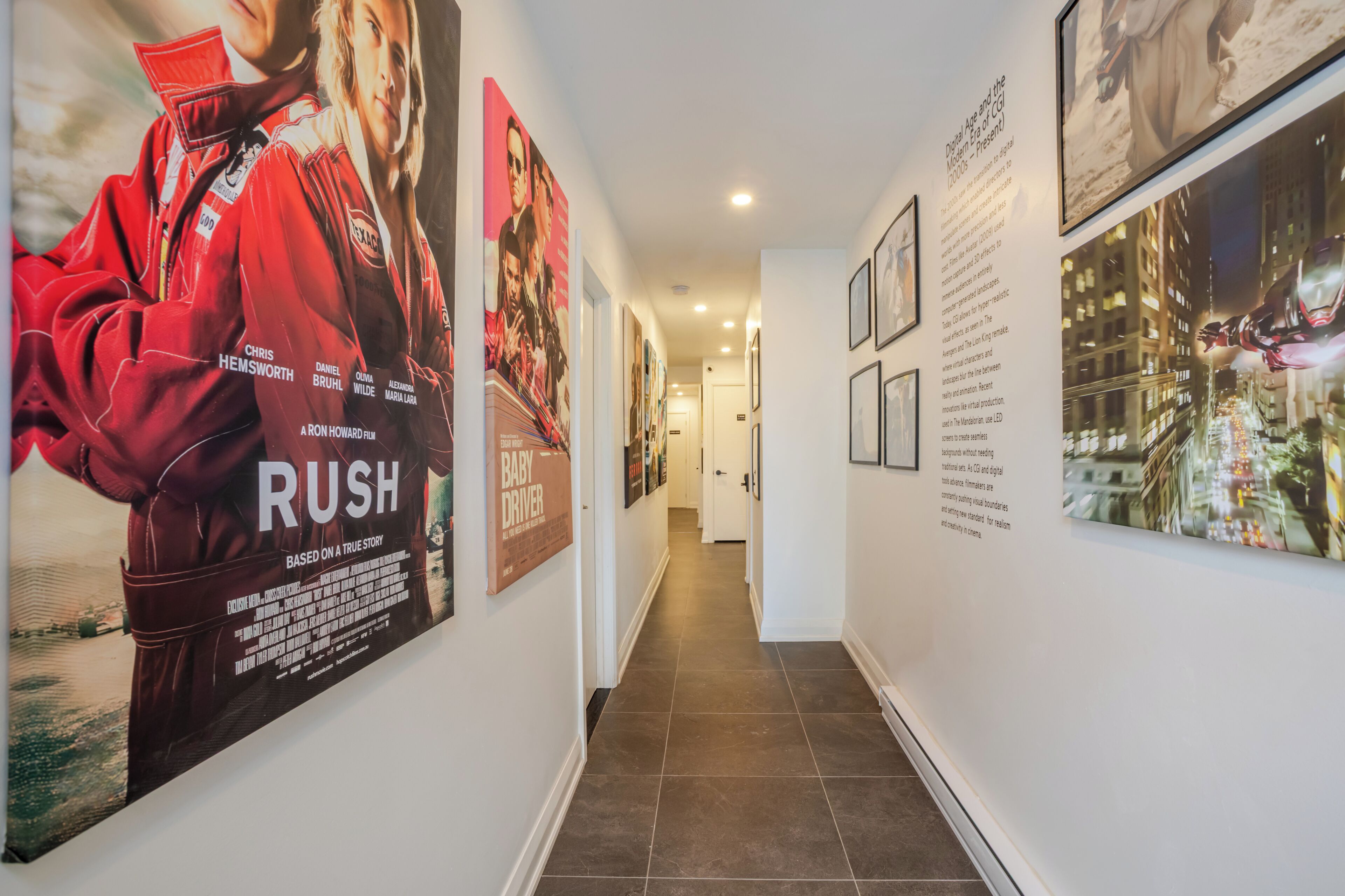 Un pasillo con carteles de películas, suelo de baldosas y cuadros en las paredes.
