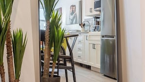 Una cucina moderna con mobili bianchi, un frigorifero in acciaio inossidabile e un'area pranzo con una sedia e un tavolo.