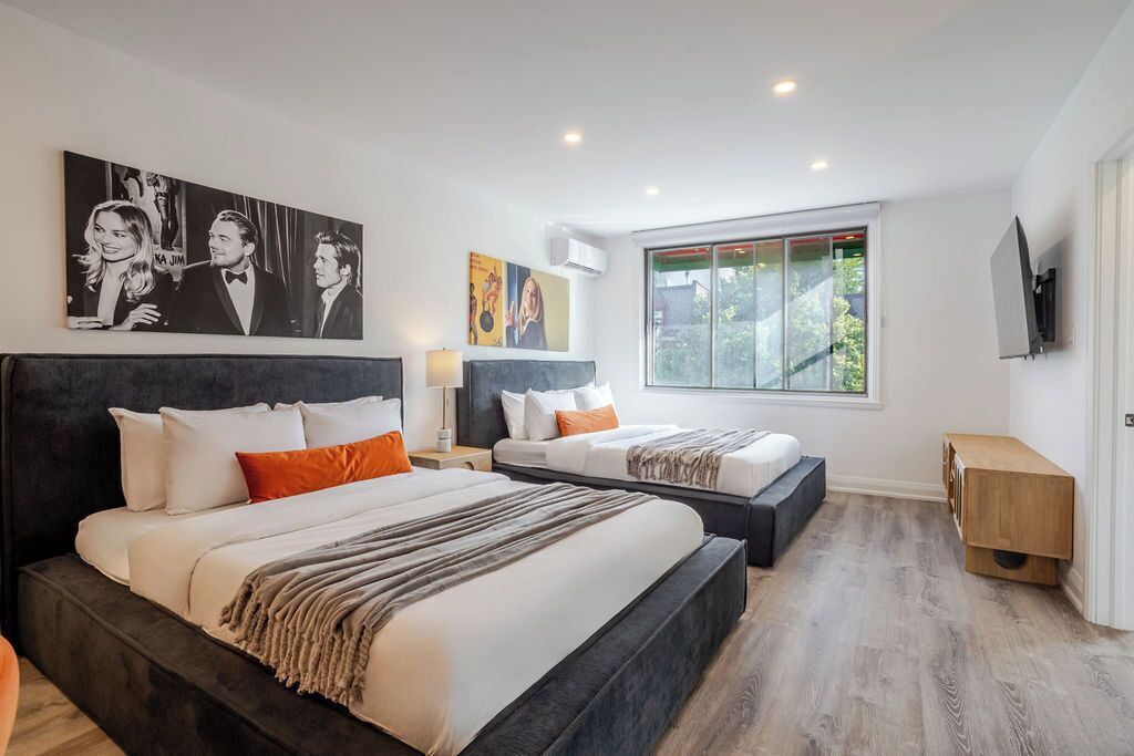Une chambre d’hôtel moderne avec deux lits, une grande fenêtre et des œuvres d’art accrochées aux murs.