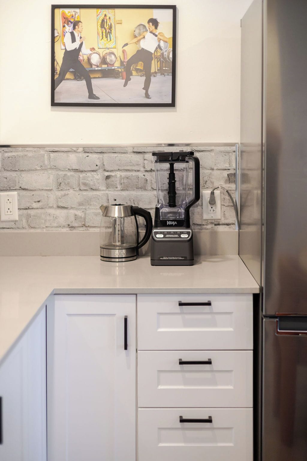 Eine Küche mit einem Mixer, einer Kaffeemaschine und einem Edelstahlkühlschrank.