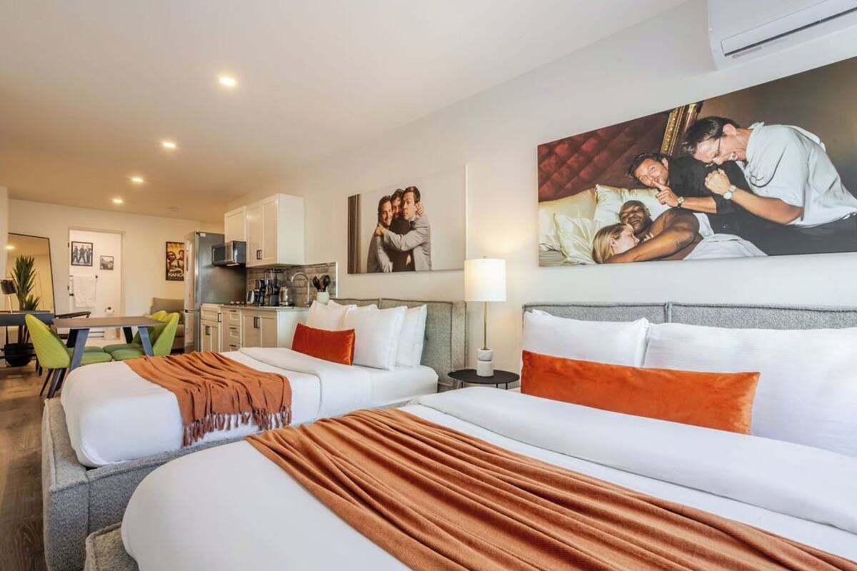 A hotel room with two beds, a dining area, and a kitchenette.