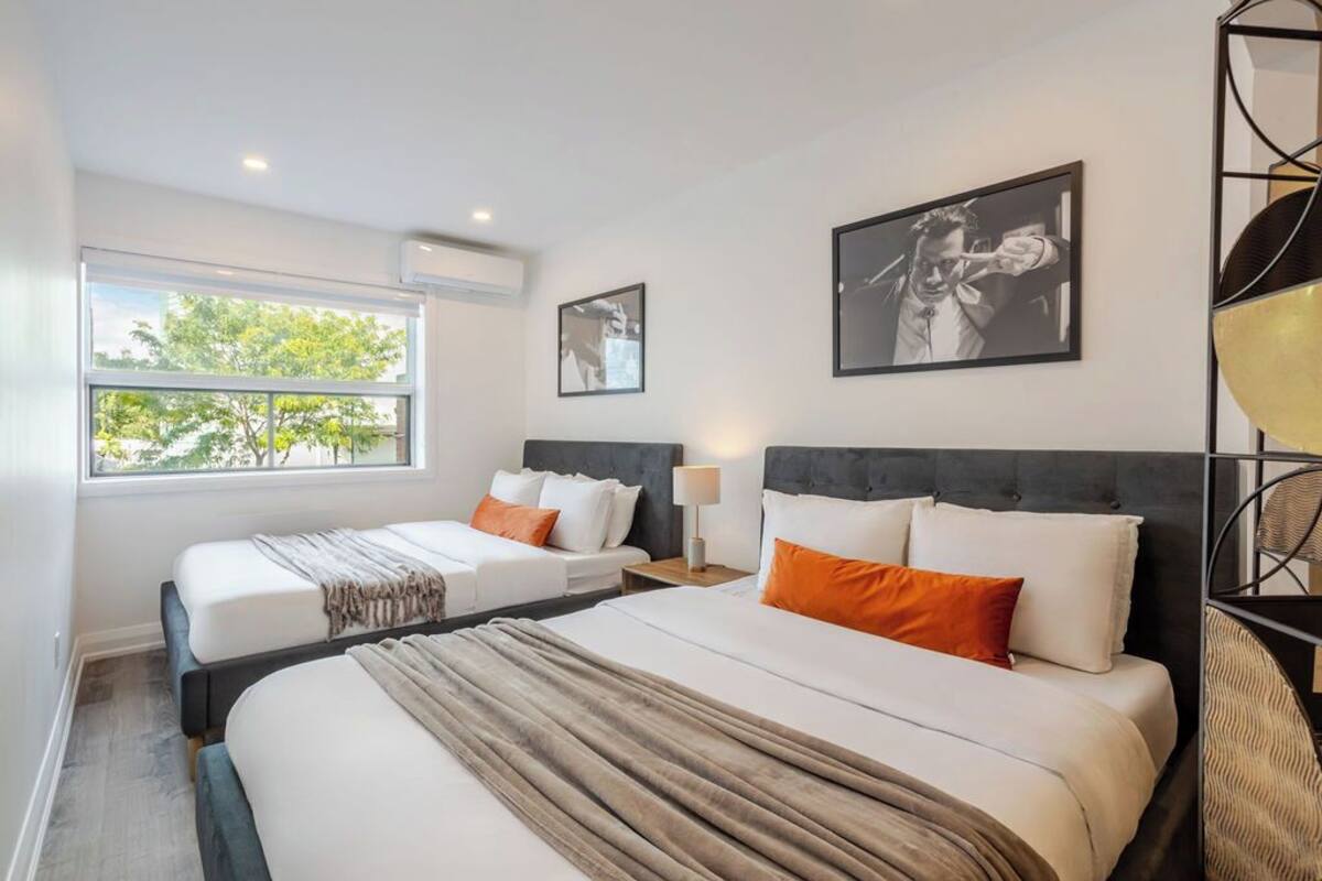 A hotel room with two beds, a large window, and artwork on the walls.