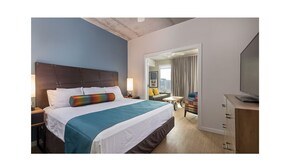 A hotel room with a bed, a TV, a desk, and a chair. - Chic Studio Deluxe Hotel Suite in the Heart of Austin (Austin)