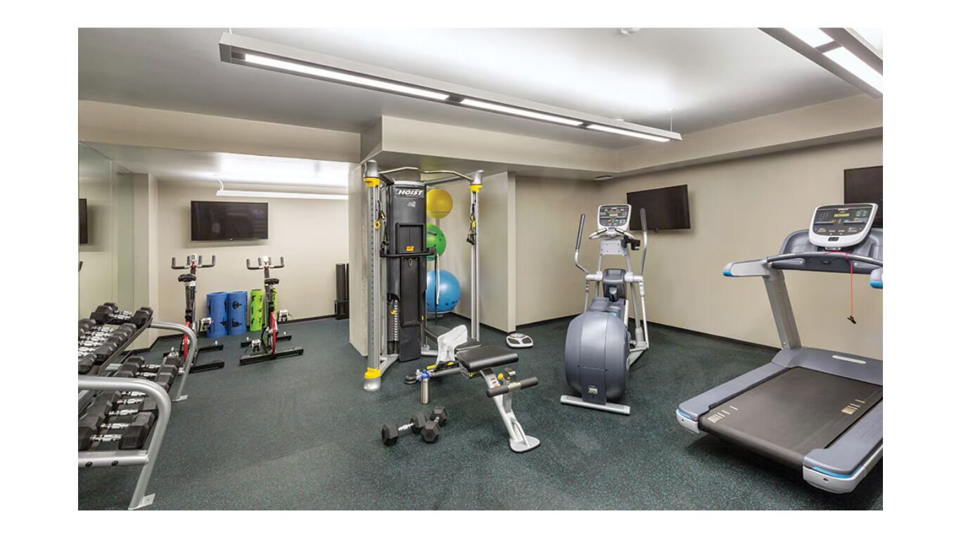 A gym with various exercise equipment including dumbbells, a treadmill, and a stationary bike.