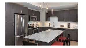 A modern kitchen with dark cabinets, stainless steel appliances, and a granite countertop. - Chic Studio Deluxe Hotel Suite in the Heart of Austin (Austin)