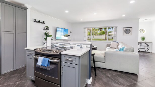 A modern kitchen with grey cabinets, a built-in stove, and a large island.
