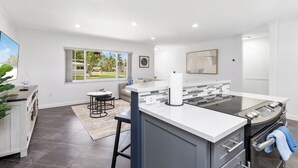A modern kitchen with a large island, built-in oven, and a view of the outdoors.