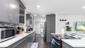 A modern kitchen with grey cabinets, stainless steel appliances, and a tiled backsplash.