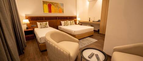 Habitación de hotel con dos camas, un sofá, una mesita y un ventilador de techo.