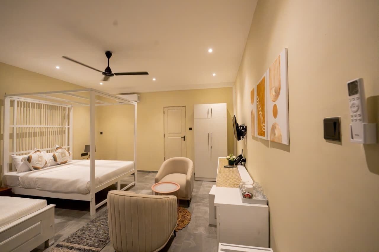 A bedroom with a four-poster bed, a chair, a desk, and a wardrobe.