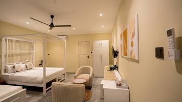 A bedroom with a four-poster bed, a chair, a desk, and a wardrobe.