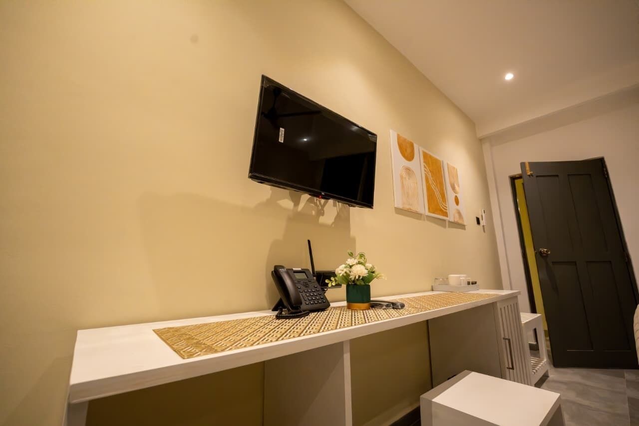 A reception area with a flat-screen TV, a phone, and a vase of flowers on a white counter.