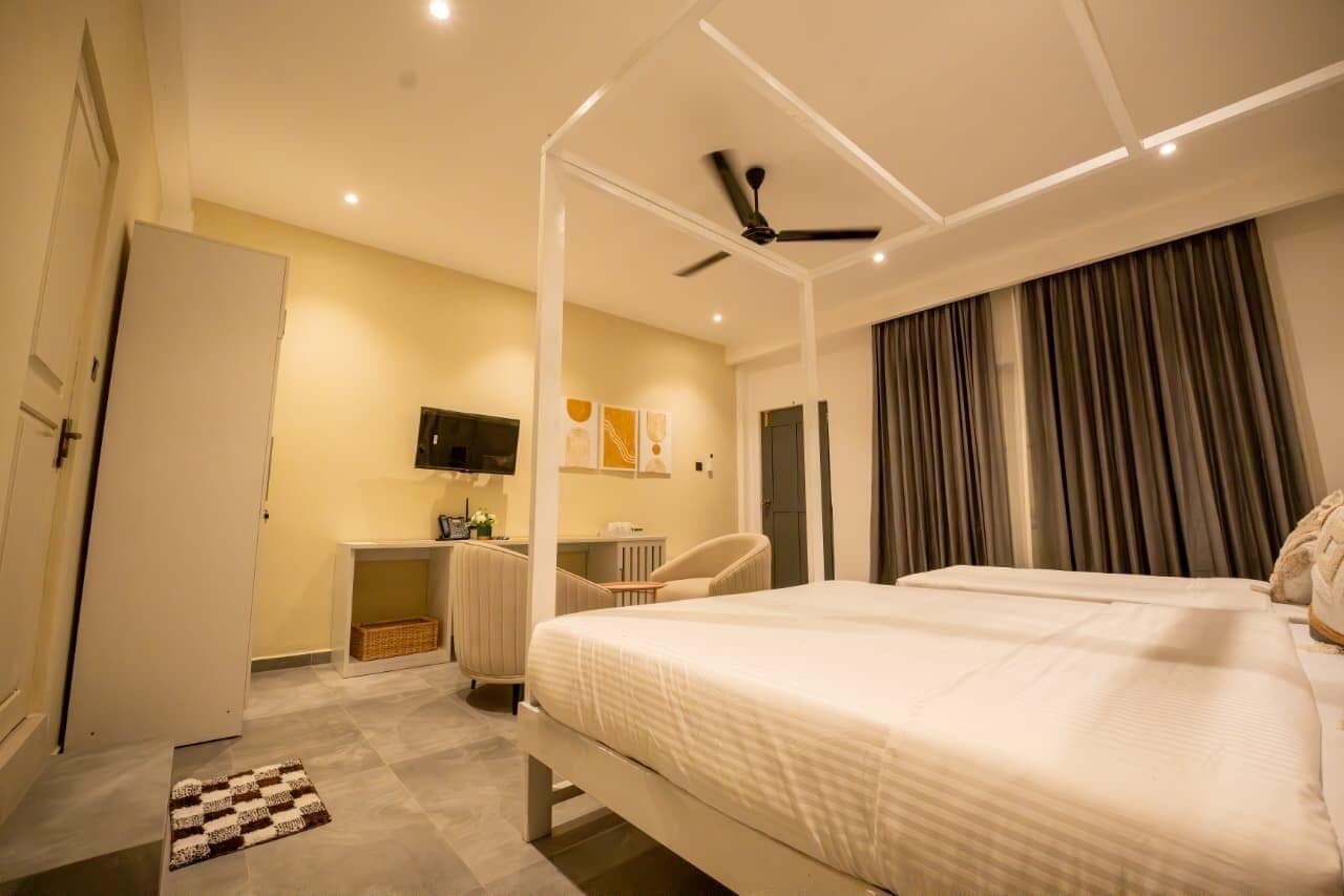 Una habitación de hotel moderna con una cama grande, un escritorio, una silla, un televisor y un ventilador de techo.