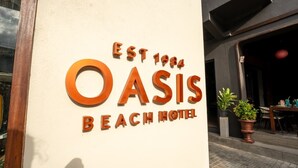 Une enseigne pour l’hôtel Oasis Beach, fondé en 1984, avec un grand logo « OASIS » et l’inscription « HÔTEL DE PLAGE ».