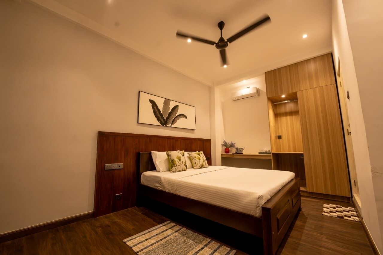 Un dormitorio con una cama de madera, un ventilador de techo, aire acondicionado de pared y un armario de madera.
