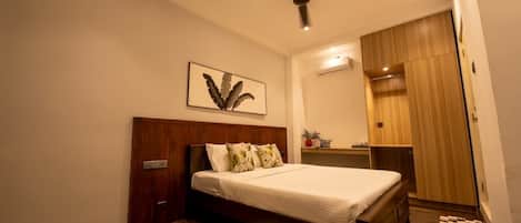 Un dormitorio con una cama de madera, un ventilador de techo, aire acondicionado de pared y un armario de madera.