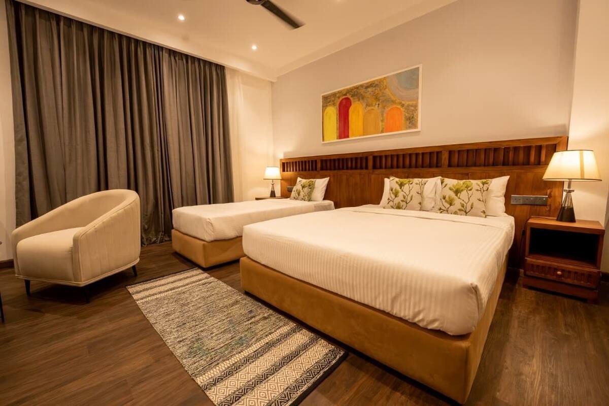 A hotel room with two beds, a chair, a rug, and a painting on the wall.