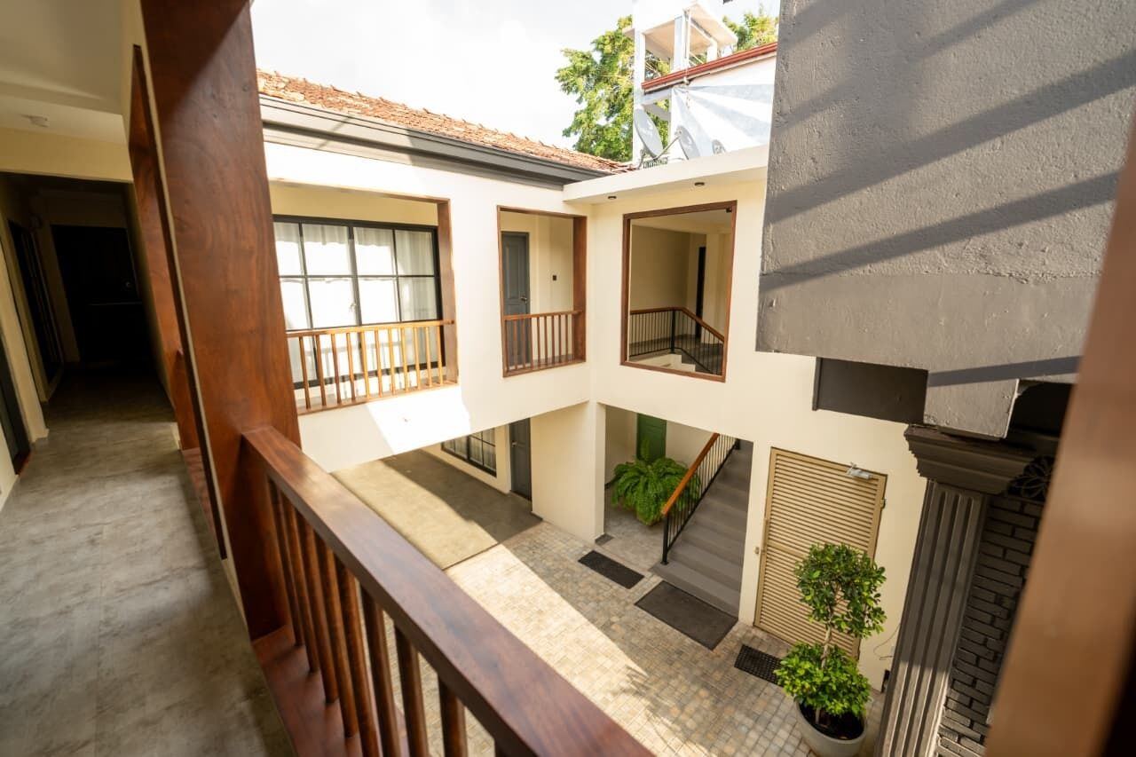 A courtyard with a wooden railing, a staircase, and potted plants.