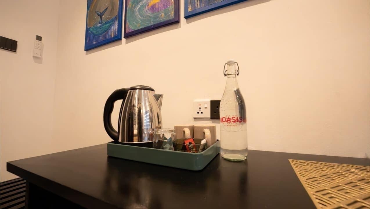 Une table avec une bouilloire, une bouteille étiquetée « OASIS » et un plateau contenant divers objets.