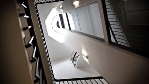Interior moderno com escada, corrimão e luminária.