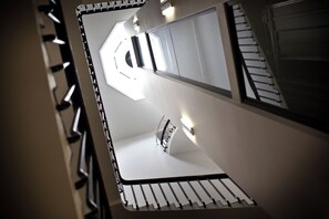 Un intérieur moderne avec un escalier, une rampe et un luminaire.