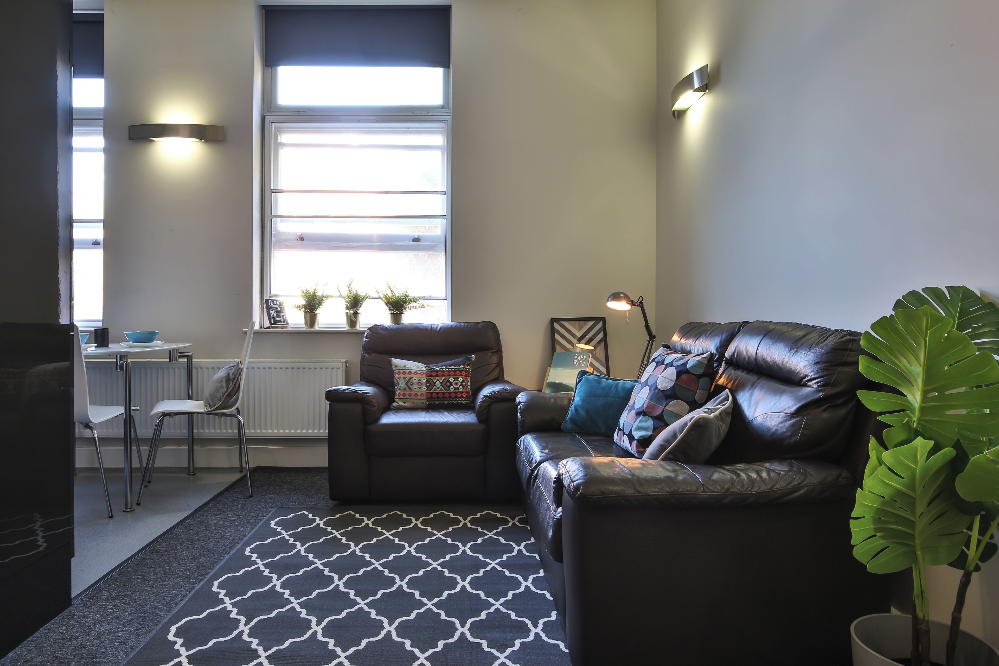 A living room with a sofa, armchair, and a dining area with chairs and a table.