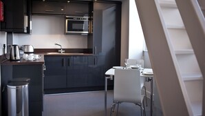 Una cocina moderna con gabinetes oscuros, un horno de acero inoxidable y una mesa de comedor blanca con sillas.