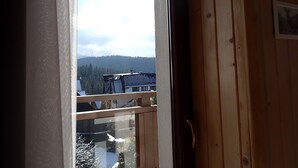 Puinen sisustus, josta avautuu näkymä lumiselle vuorelle ja joen toisella puolella sijaitsevaan rakennukseen.